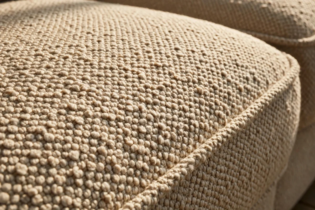 An oatmeal looped-weave sofa in warm sunlight showing nubby texture