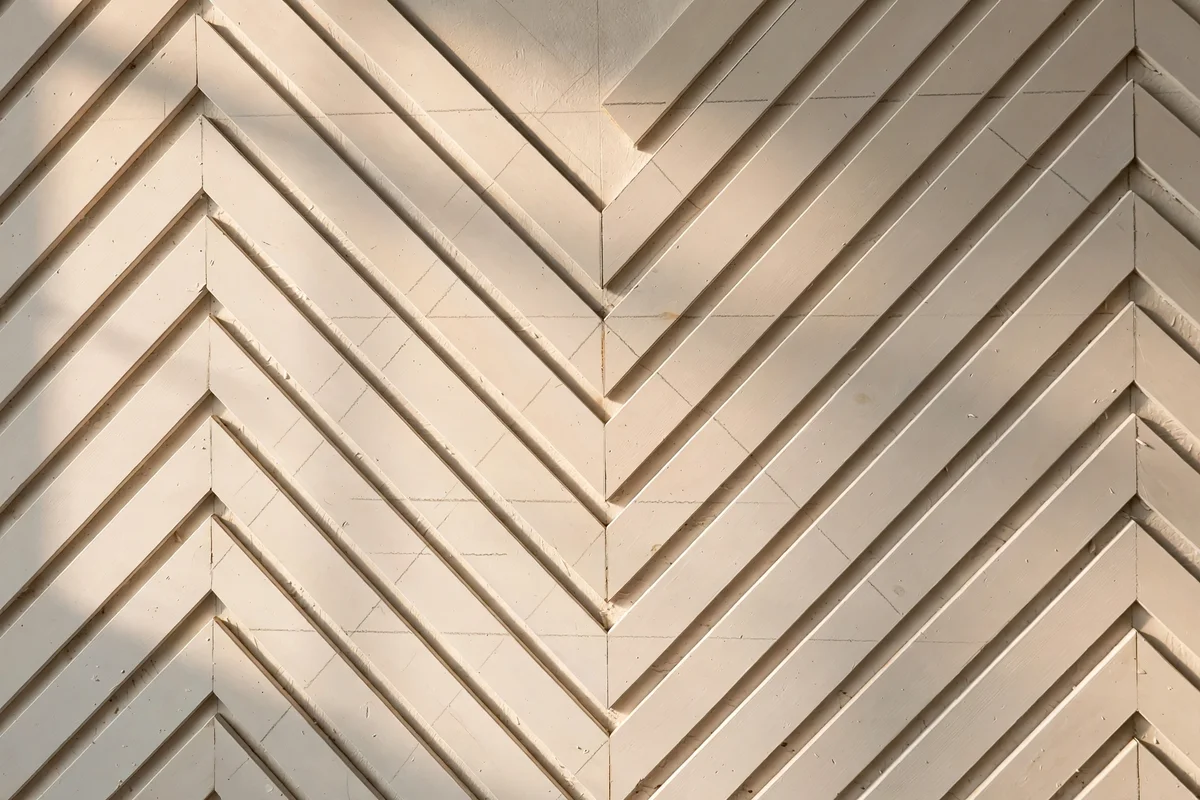 Wall with slim battens in a herringbone pattern painted warm white