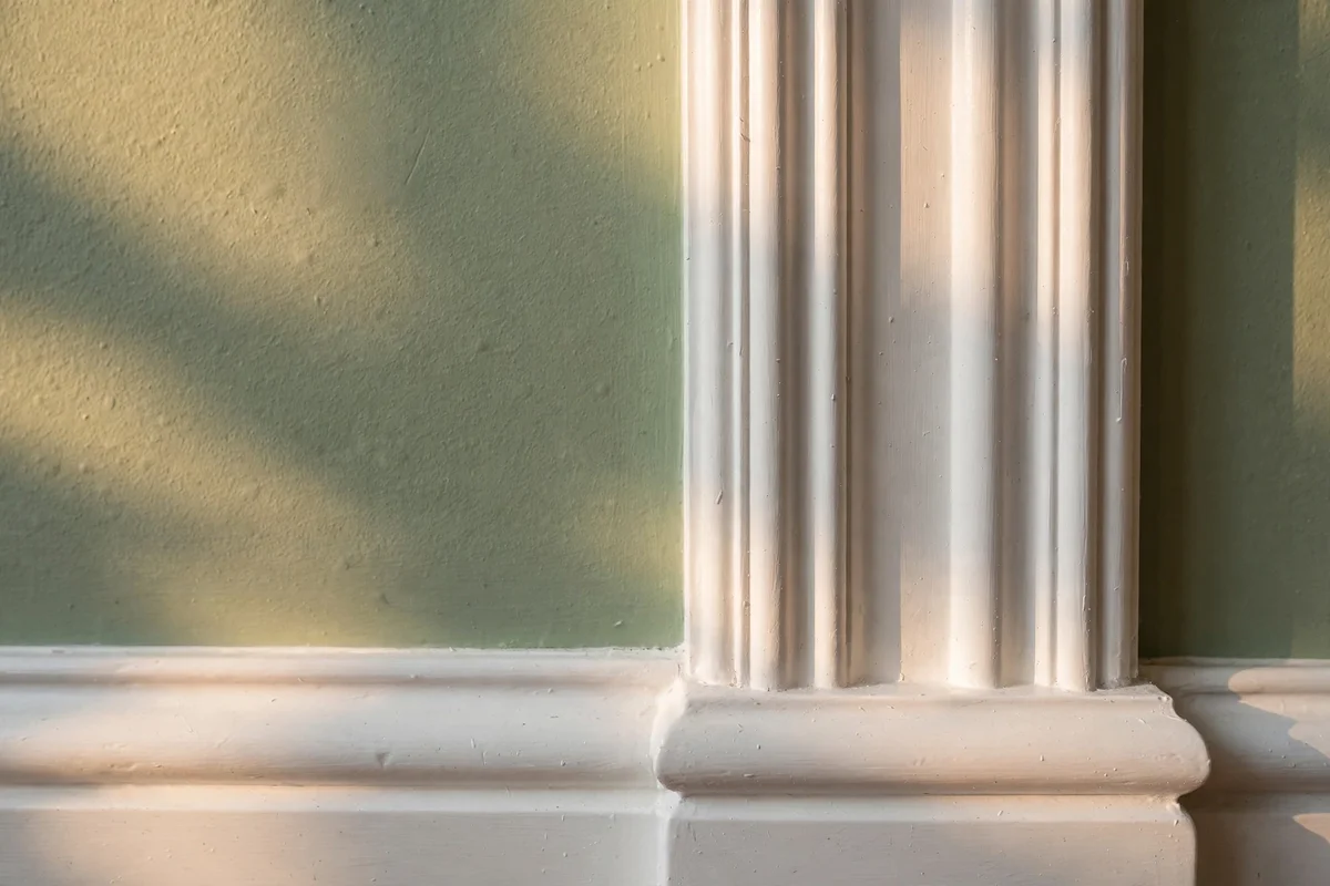 Painted skirting boards and architrave against a sage wall