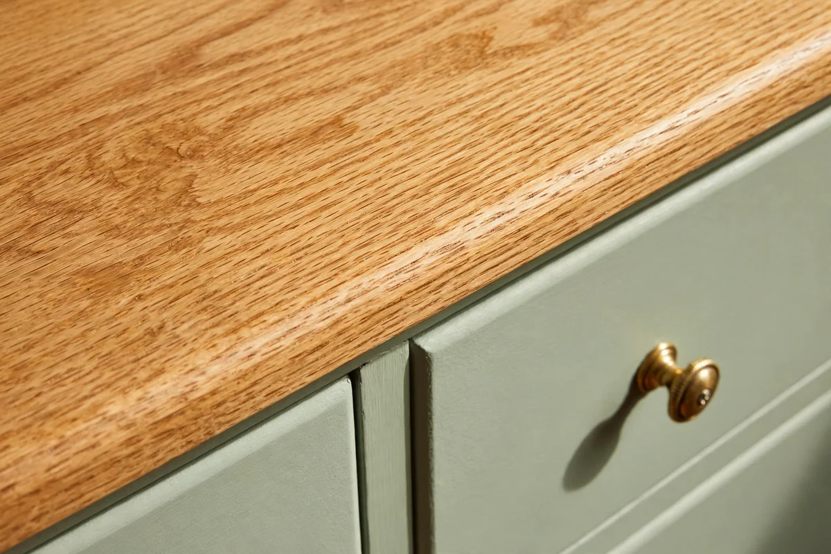 Oak dresser top with honey stain showing grain beside a soft sage painted drawer