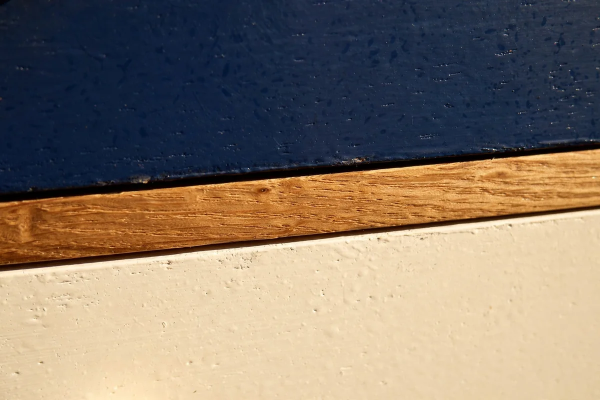 Drawer front detail with navy and cream paint separated by a slim bare wood line